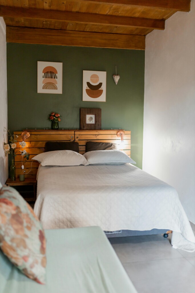 Sypialnia w nowoczesnym apartamencie z zieloną ścianą i geometrycznymi obrazami