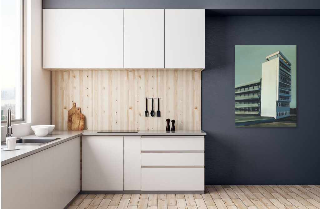 Obraz z modernistycznym budynkiem wiszący na ciemnej ścianie skontrastowany z nowoczesną jasną zabudową nowoczesnej kuchni