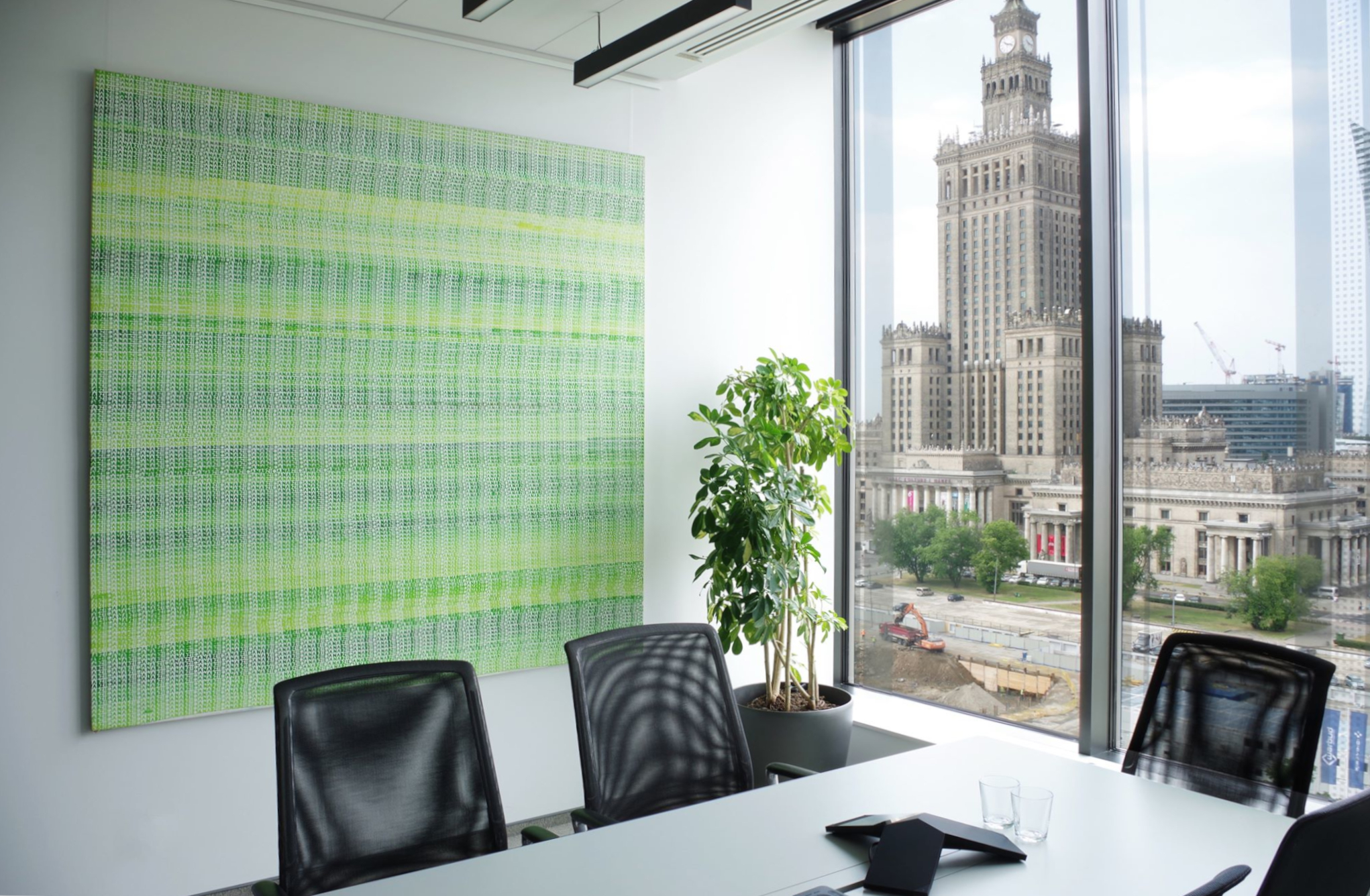 Zielony obraz wiszący w nowoczesnym biurze z widokiem na Pałac Kultury i Nauki.