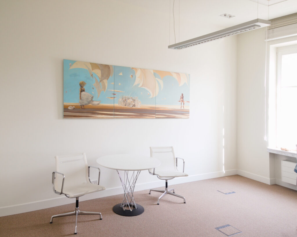 Podłużny obraz wisi w biurze przedstawiąa dziewczynkę w pejzażu.